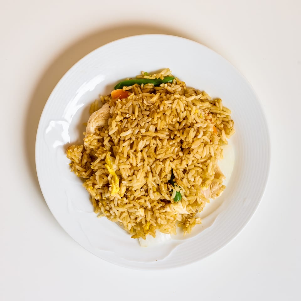 Plate of golden fried rice with chicken, scrambled egg, carrots, and green beans.
