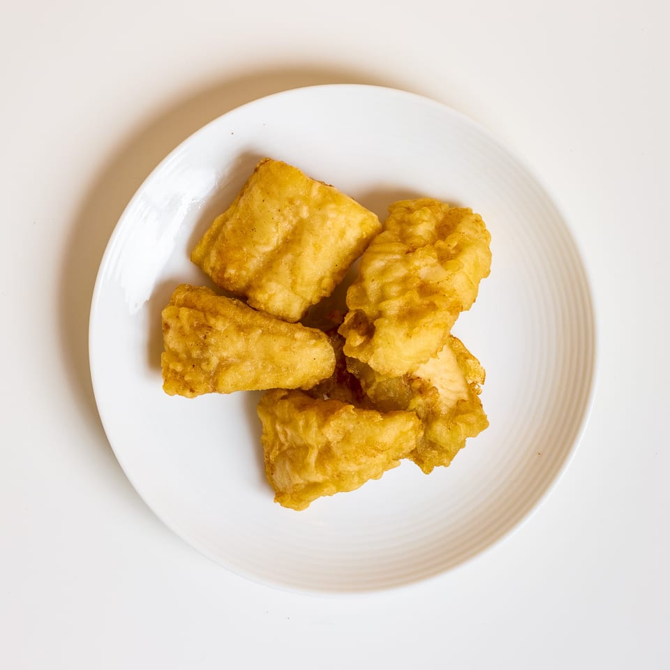 Golden fried battered pieces arranged on a white plate.