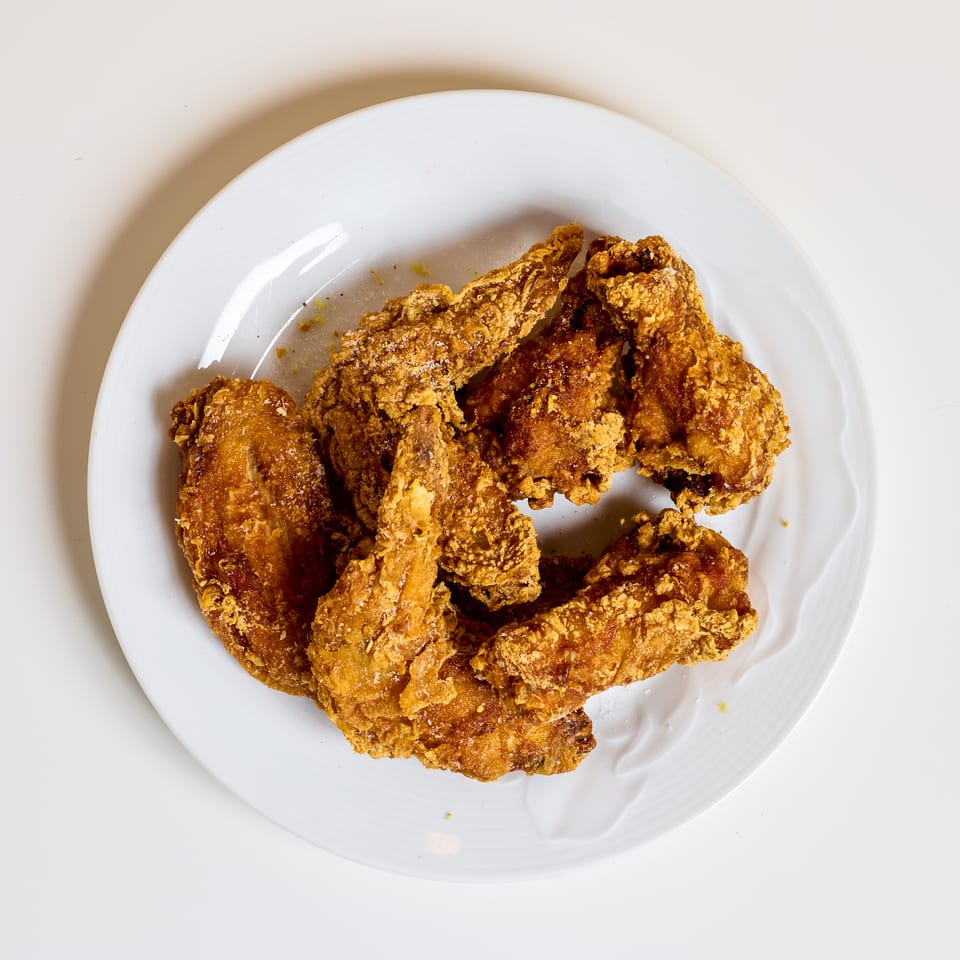 Plate of golden-brown crispy fried chicken pieces arranged on a white plate.
