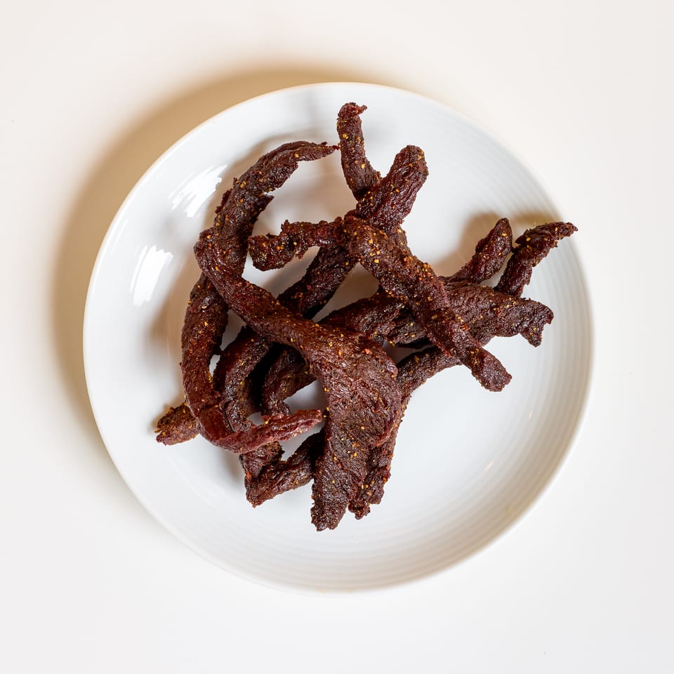Plate of dark, spiced strips of dried meat arranged on a white dish.